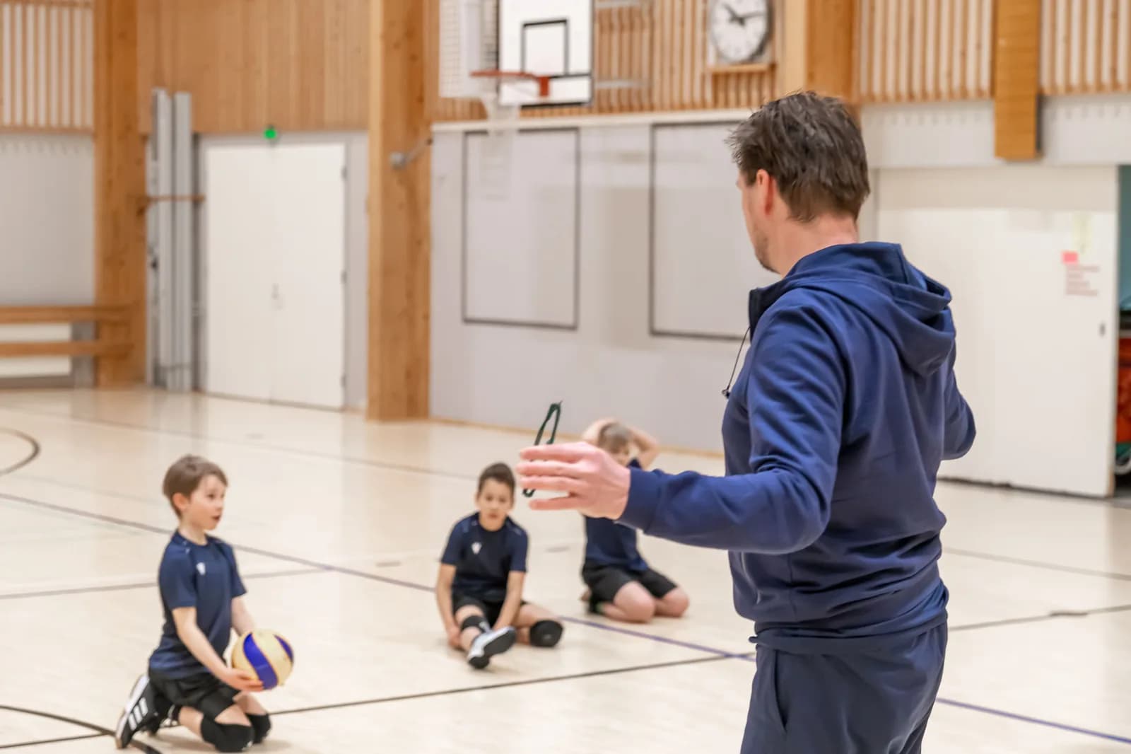 Valmentaja ja junioripojat salin lattialla